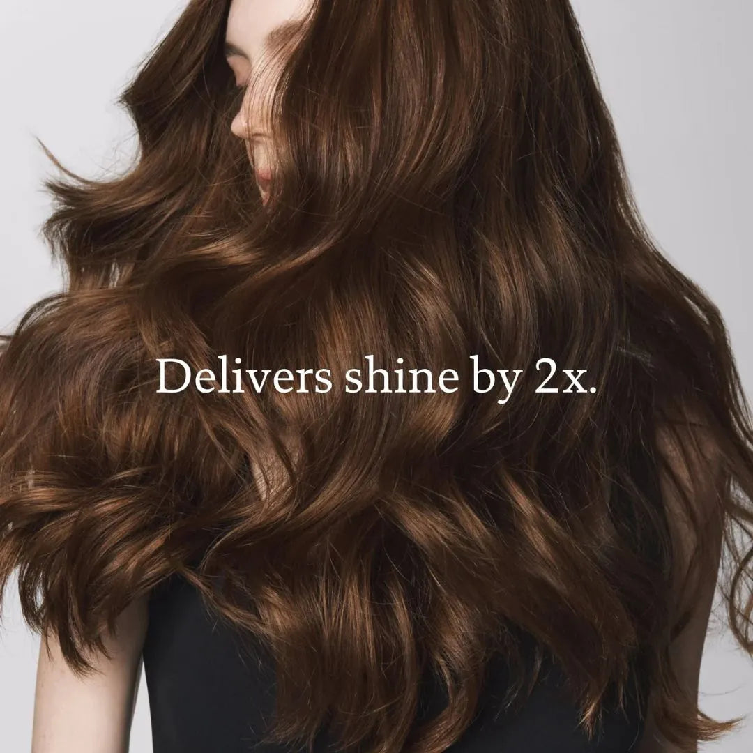 Close-up of wavy brown hair with text 'Delivers shine by 2x.' on a neutral background