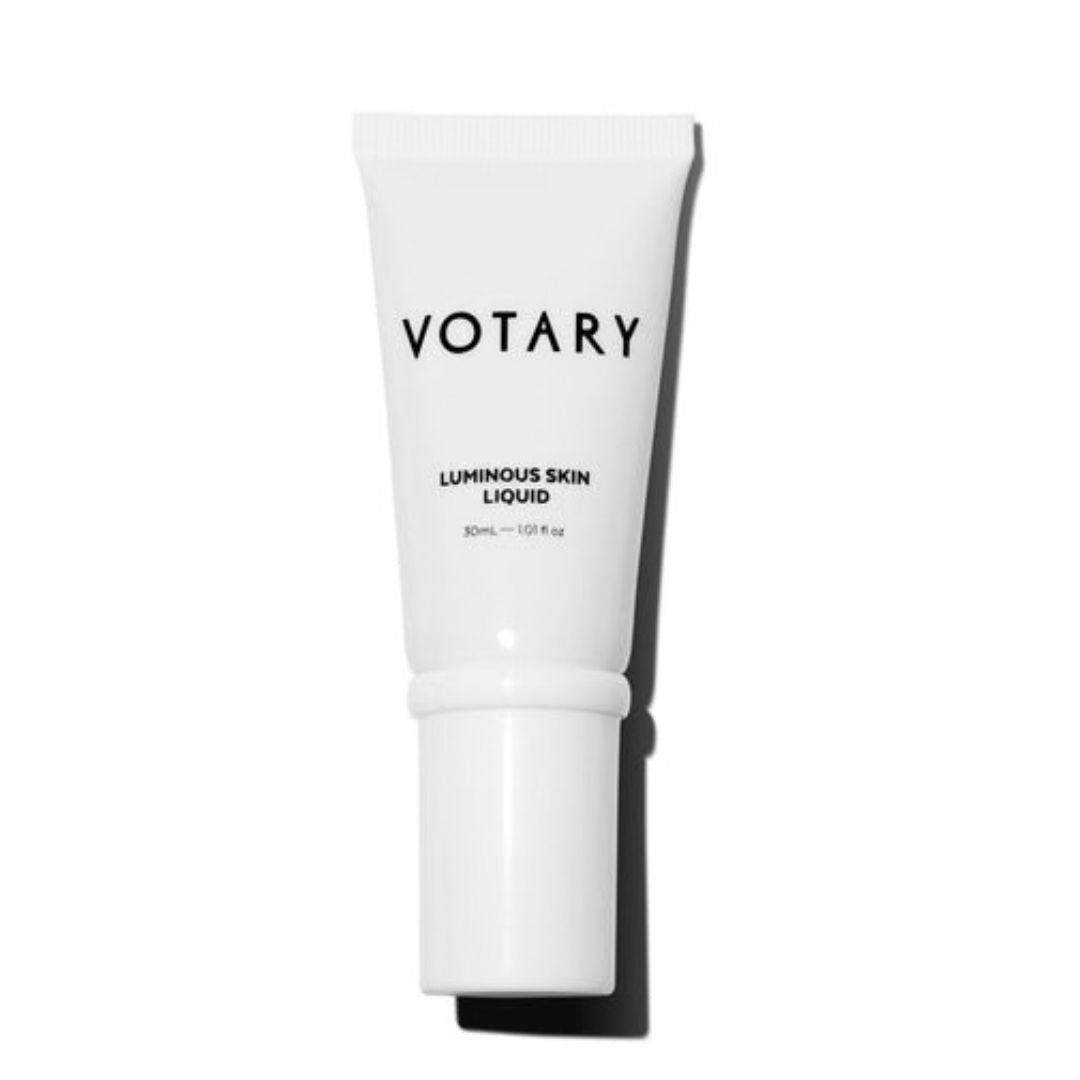 A white squeeze tube of VOTARY Luminous Skin Liquid on a clean white background with a soft shadow.