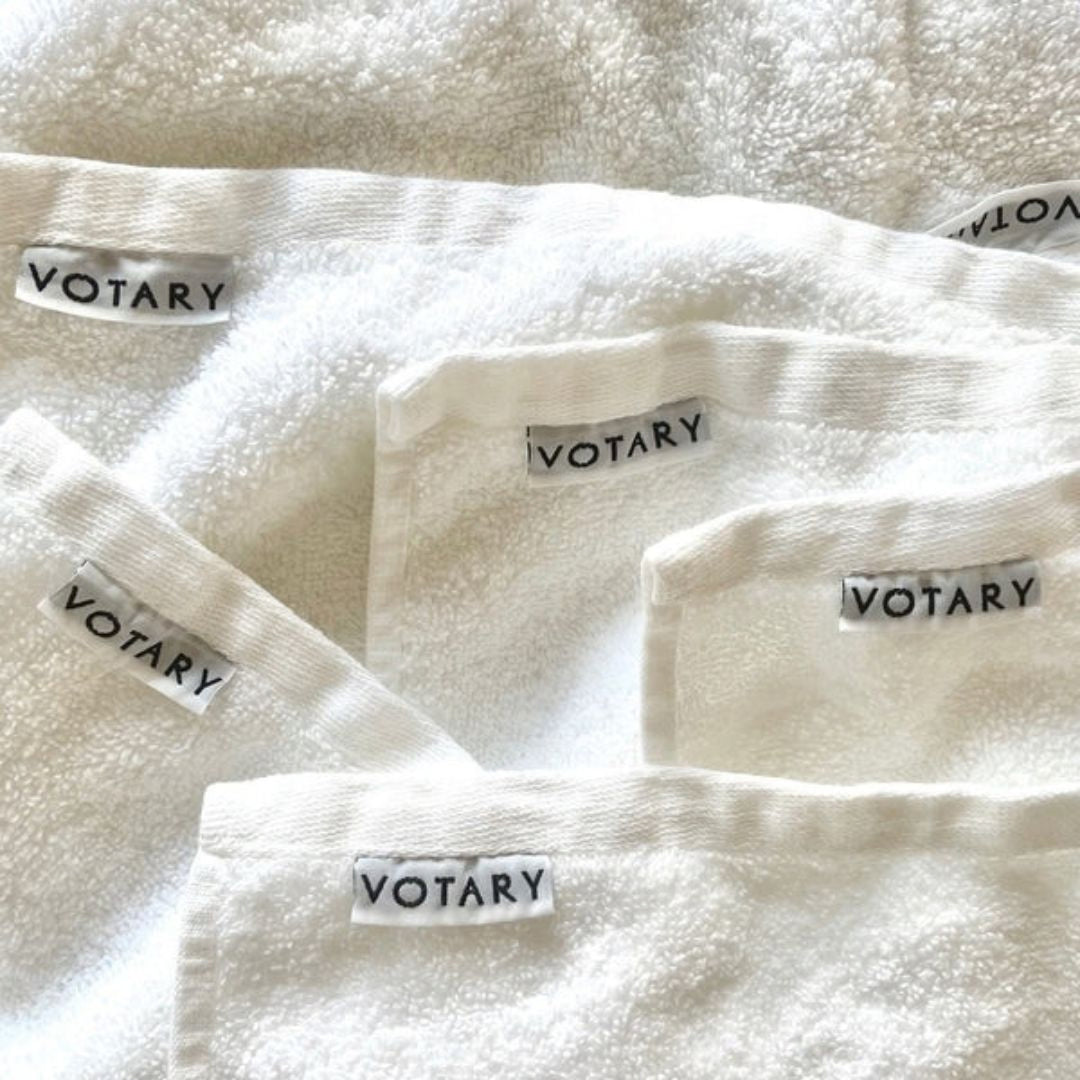 Close-up of soft white Votary Face Cloths with branded Votary labels