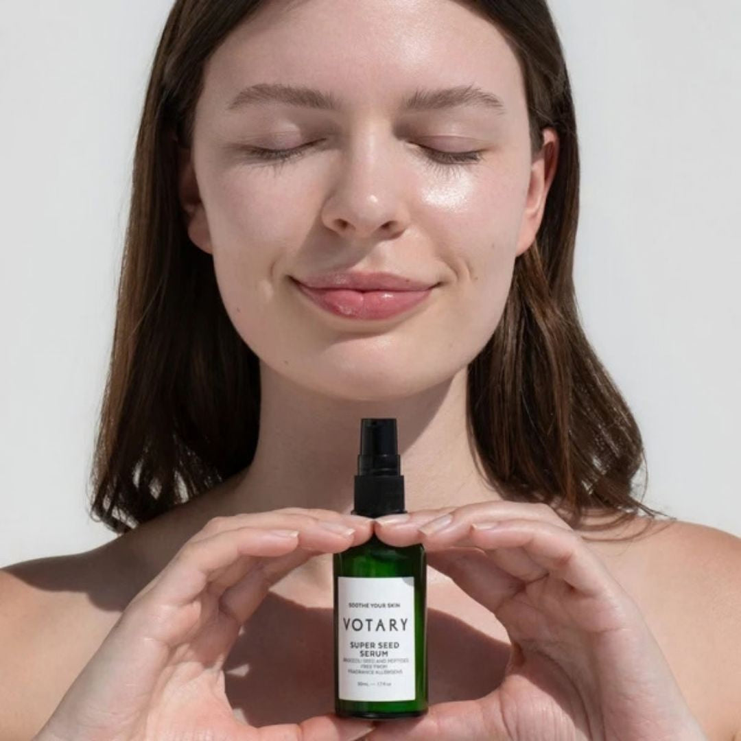 Votary Super Seed Serum with broccoli seed and peptides held by model with calm, radiant-looking skin