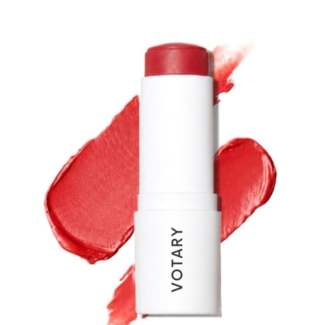 VOTARY Lip and Cheek Tint-TeaRose stick in a white tube with a red cap, shown in front of red cream makeup smears on a white background.