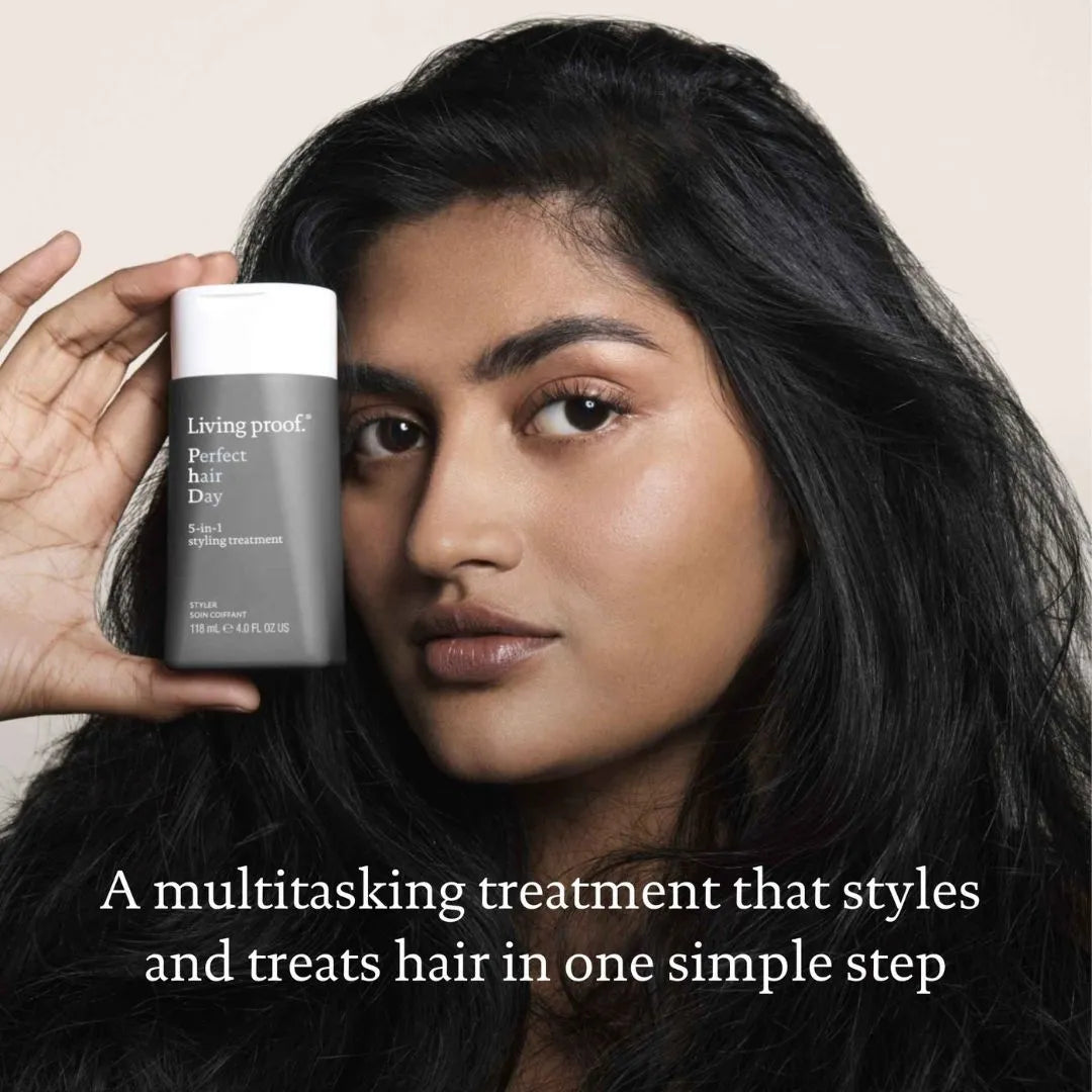 Living Proof Perfect Hair Day 5-in-1 Styling Treatment 118ml – lifestyle shot: model holding bottle with multitasking treatment claim on light background
