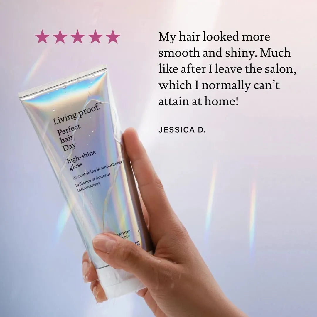 Hand holding a Living Proof hair product with a five-star rating and customer review on a light background