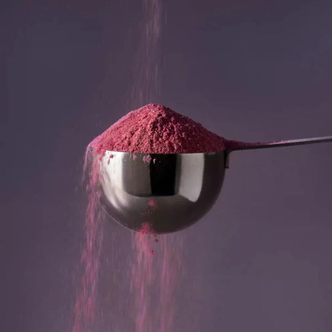 JSHealth Advanced Sleep+ Calm Night Tonic Powder 120g – powder texture close-up: magenta-pink powder with scoop on dark purple background