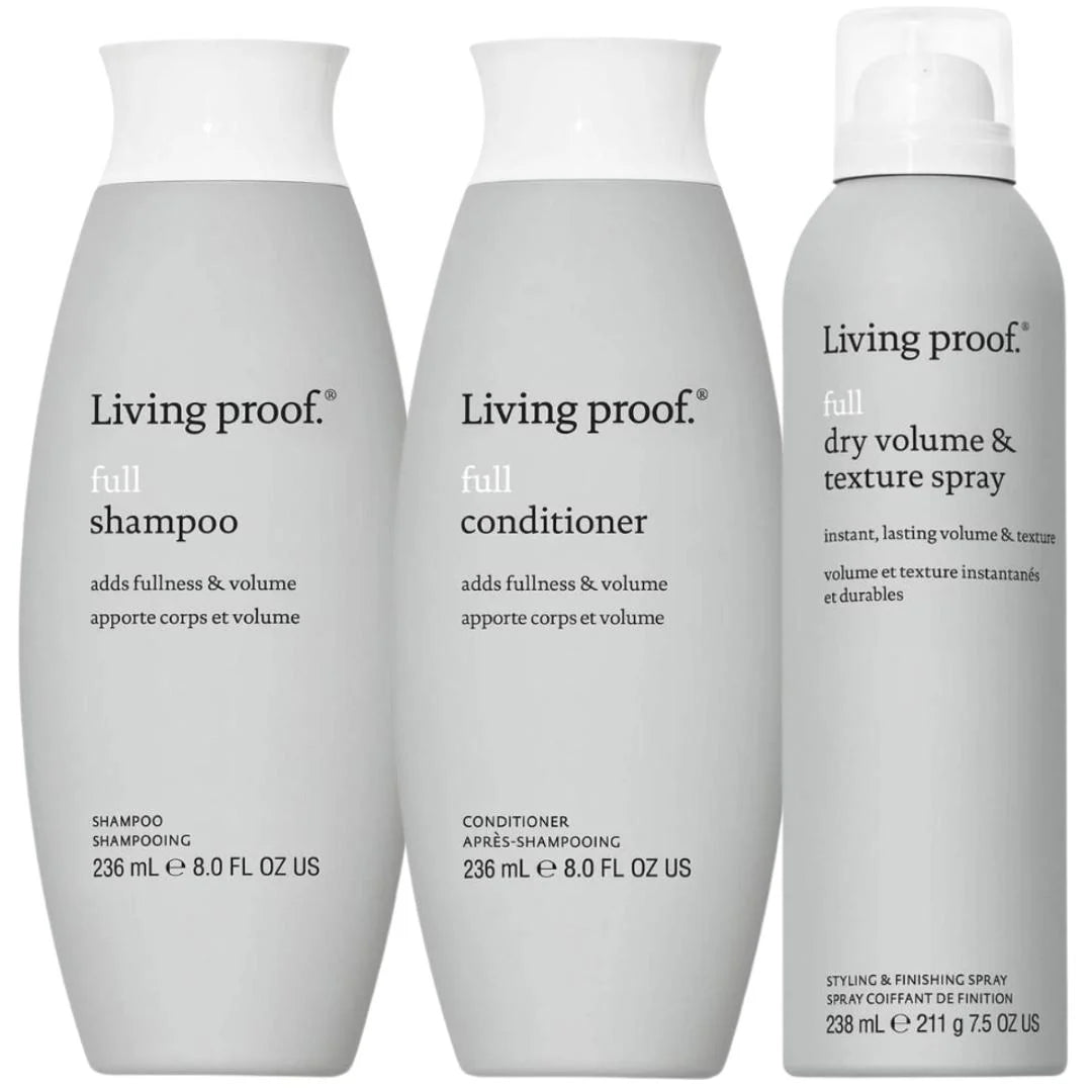 Three Living proof hair care bottles on a plain white background: a shampoo bottle, a conditioner bottle, and a dry volume & texture spray bottle.