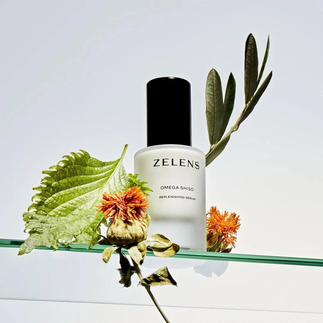 Zelens Omega Shiso Replenishing Serum 30ml – lifestyle product shot on glass shelf with botanicals against light grey background