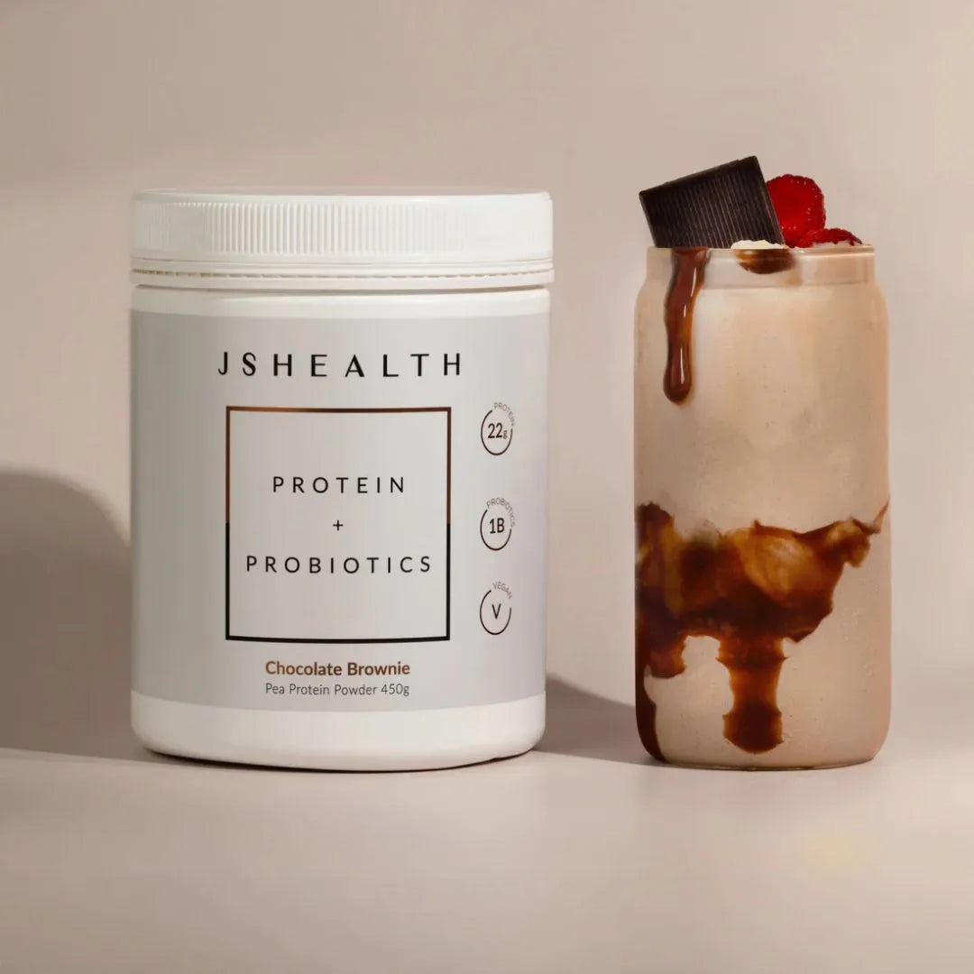 JSHealth protein and probiotics container next to a dessert with chocolate sauce on a beige background