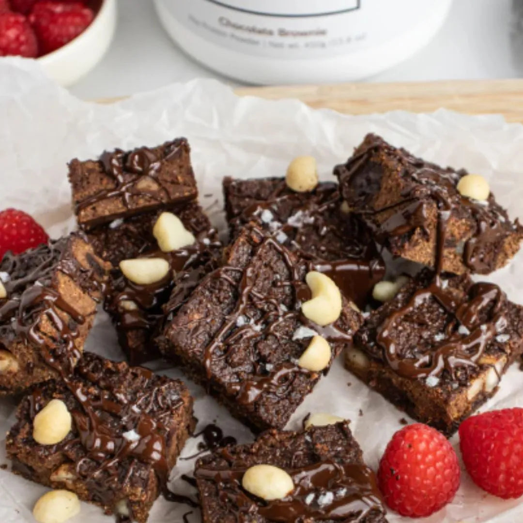 Brownies with white chocolate chips and raspberries on a white surface