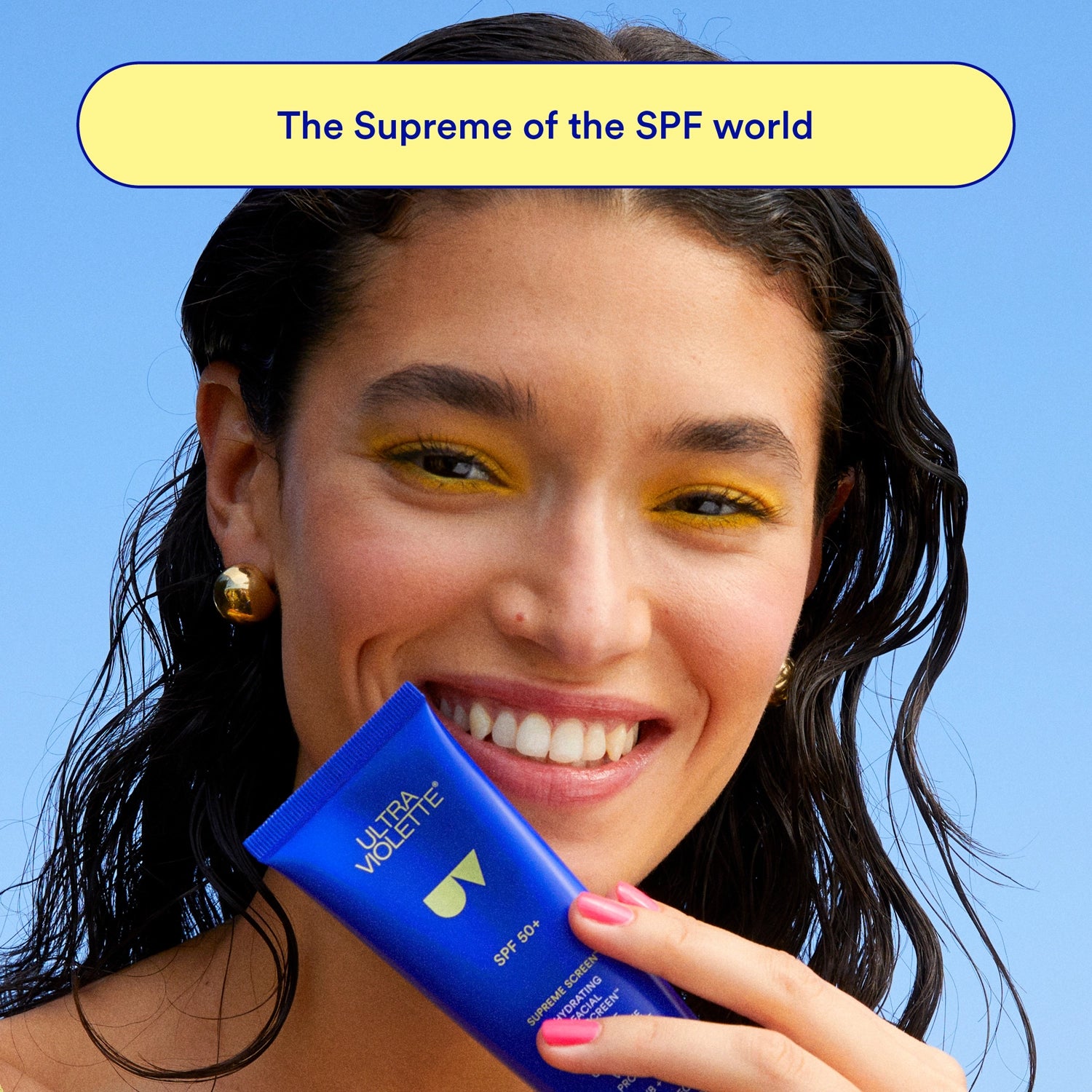 Woman holding a blue Ultra Violette sunscreen tube with a blue background