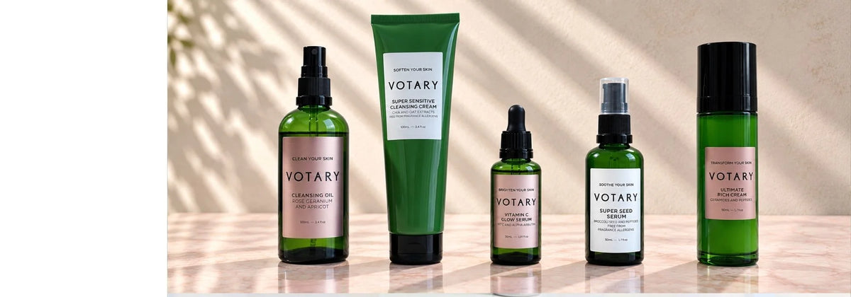 Votary skincare collection featuring cleansing oil, cleansing cream, vitamin C serum, seed serum, and rich cream in green glass bottles.