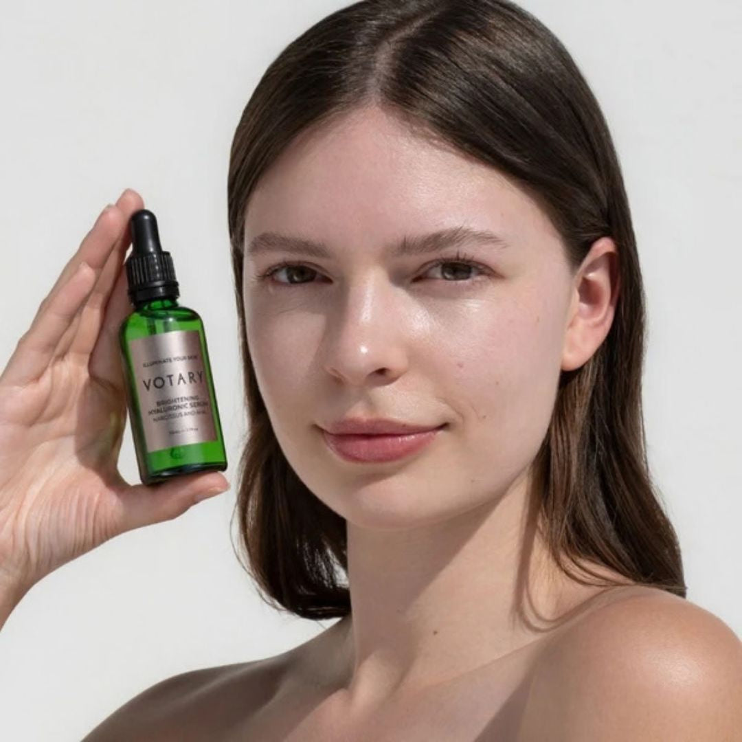 Votary Brightening Hyaluronic Serum held beside model showing hydrated, radiant-looking skin