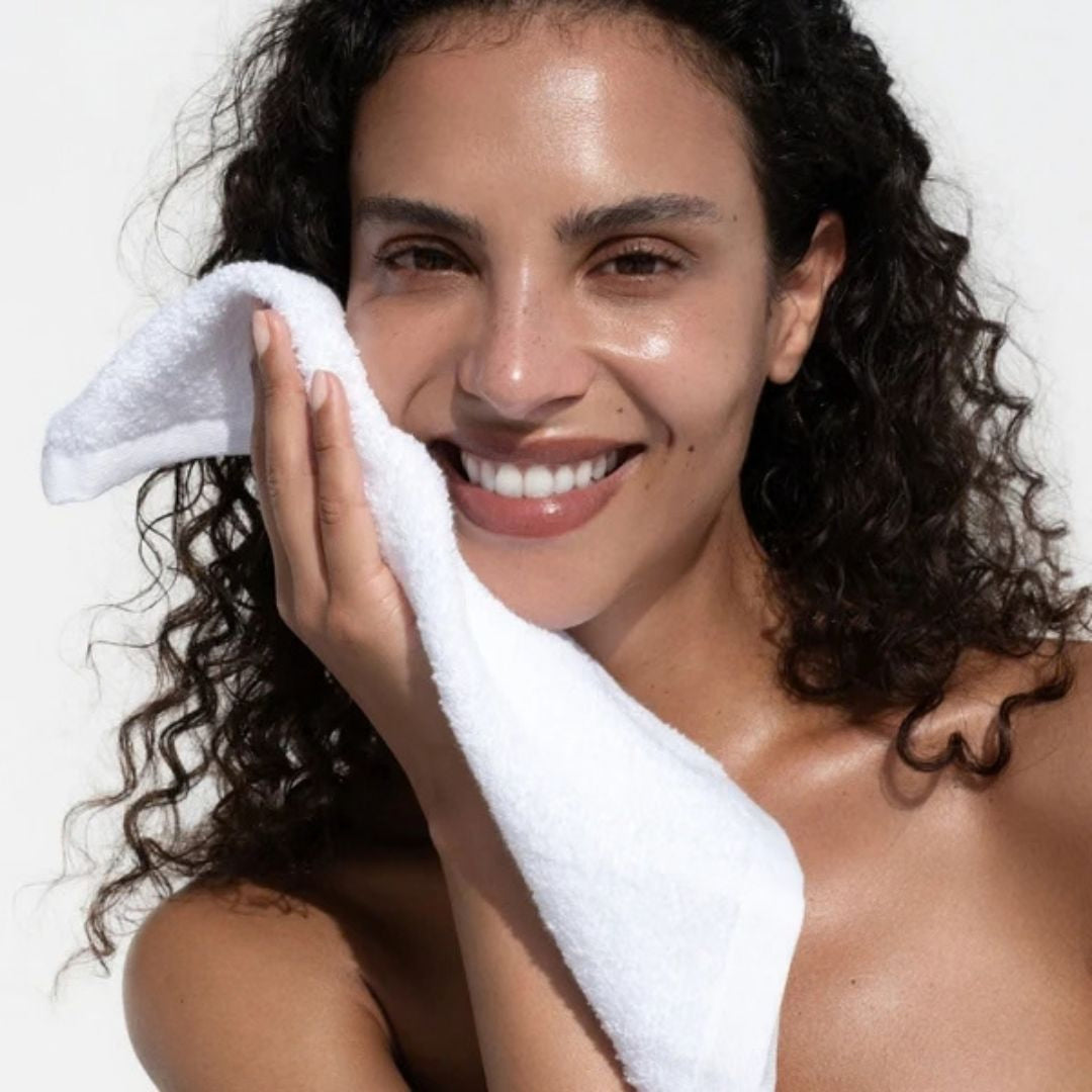 Woman gently cleansing her face with a soft white Votary Face Cloth